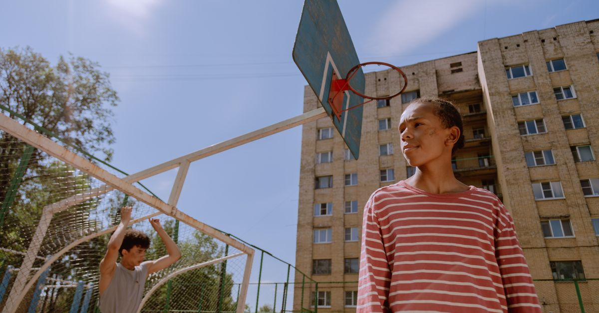 Two teenagers at an outdoor basketball court during the day.